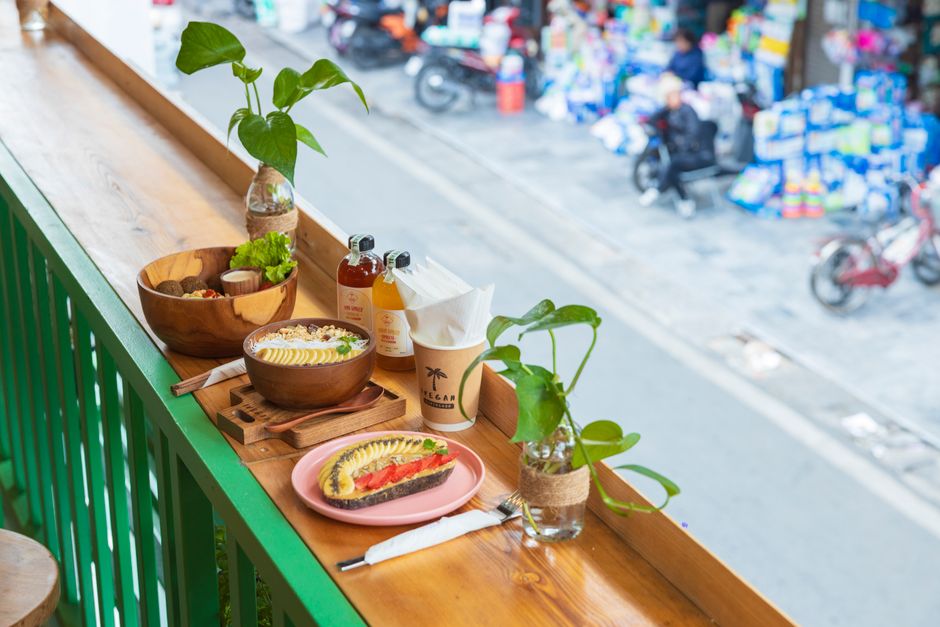 A vibrant, healthy meal of fresh fruits and salad served on a rustic wooden table on an outdoor patio overlooking a sparkling blue ocean, embodying the wellness-focused diet of Cabo.